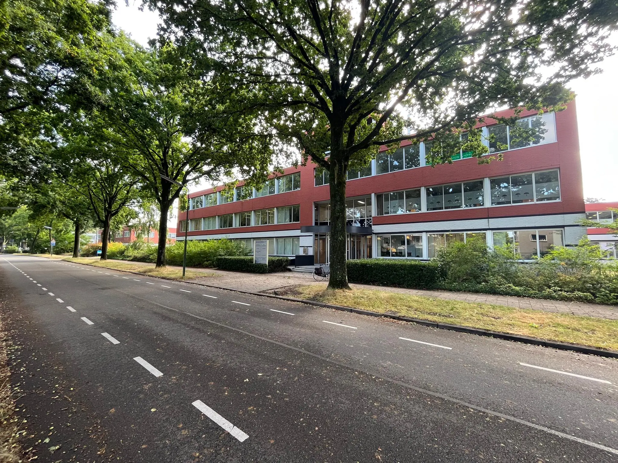 Kantoor- of schoolgebouw aan de Jan van Eycklaan met een fietspad en bomen langs de weg.